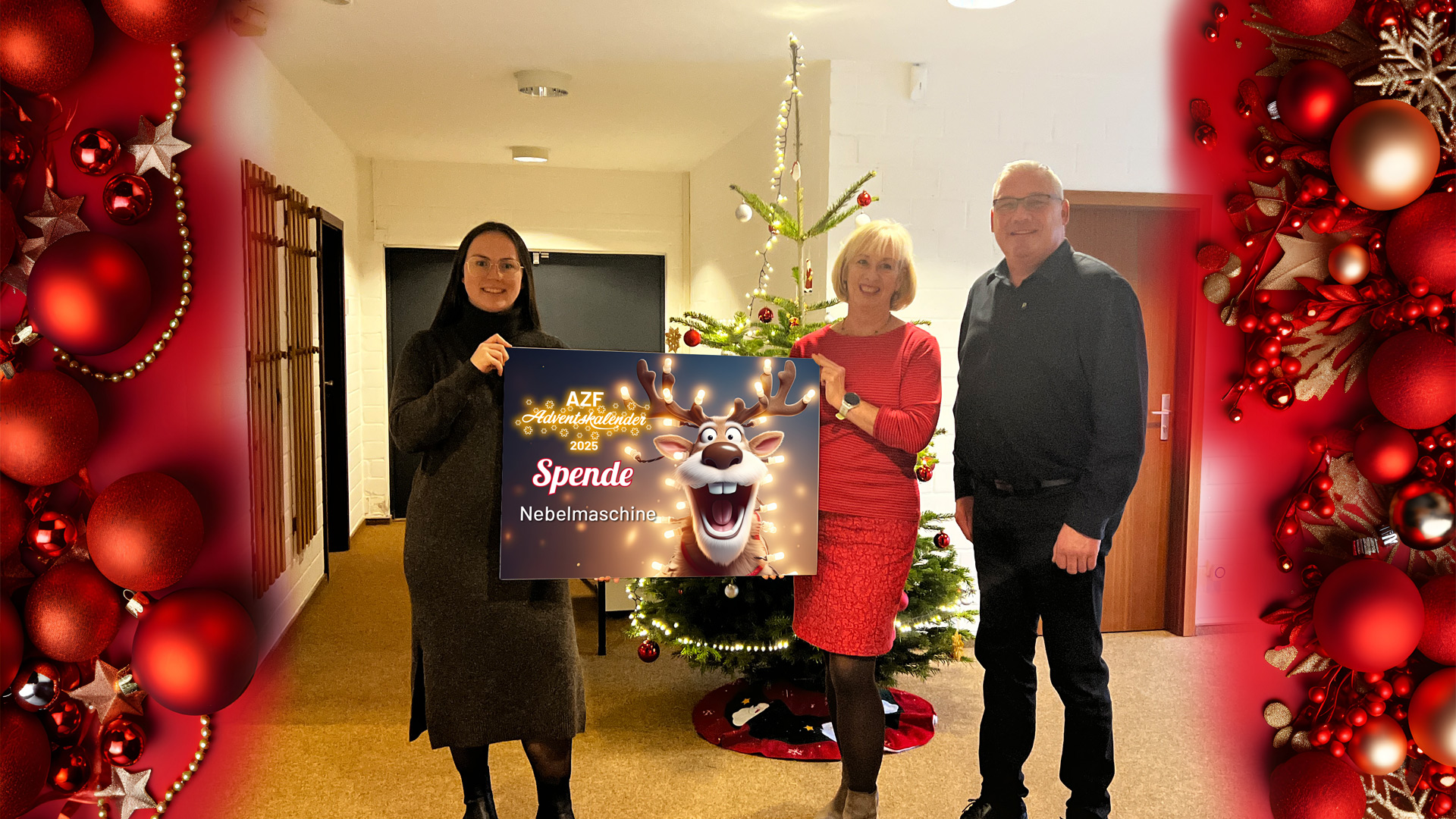 Drei Personen stehen vor einem geschmückten Tannenbaum und halten eine Spendentafel