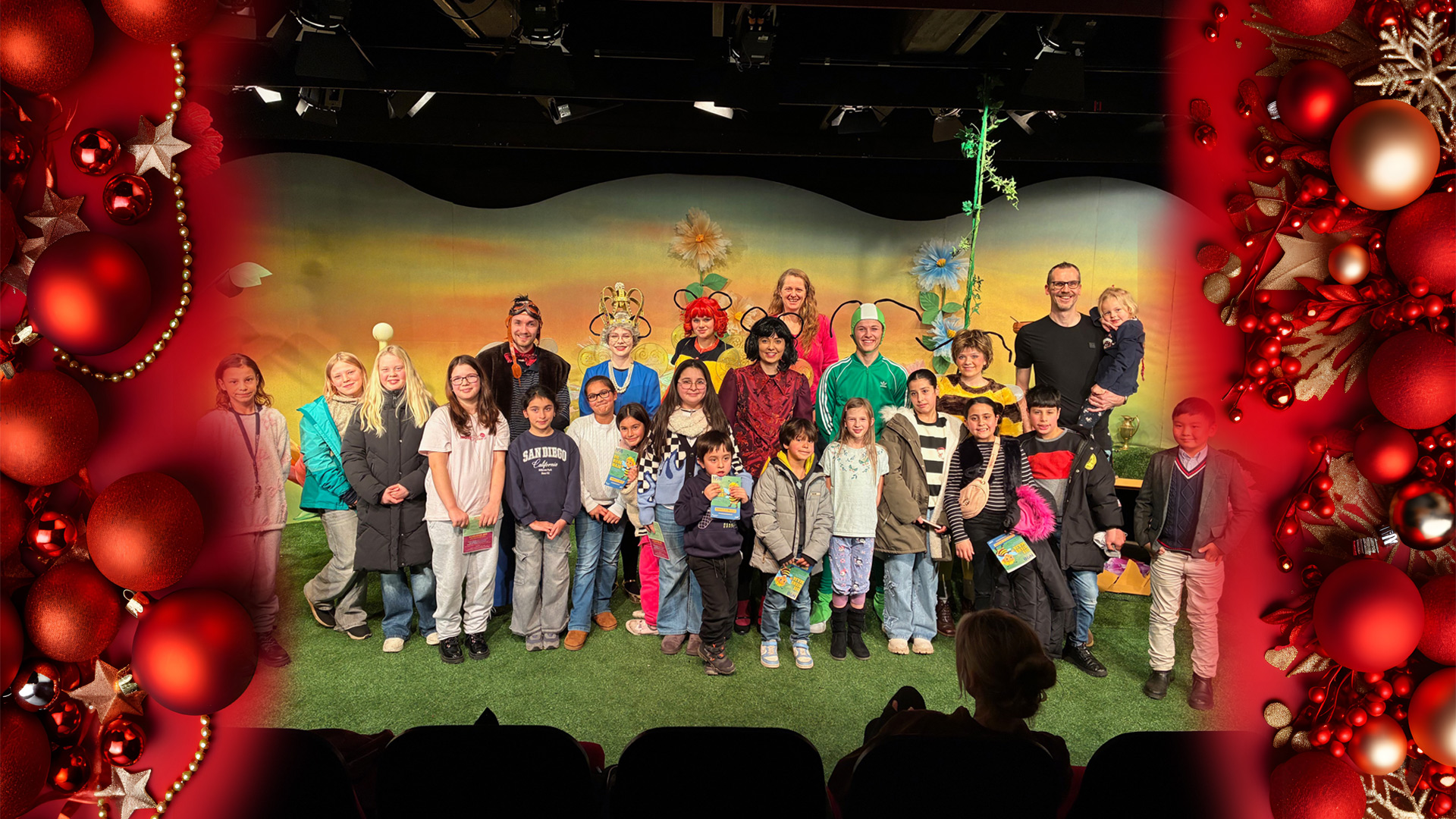 Viele Menschen, Erwachsene und Kinder stehen auf einer Theaterbühne und freuen sich