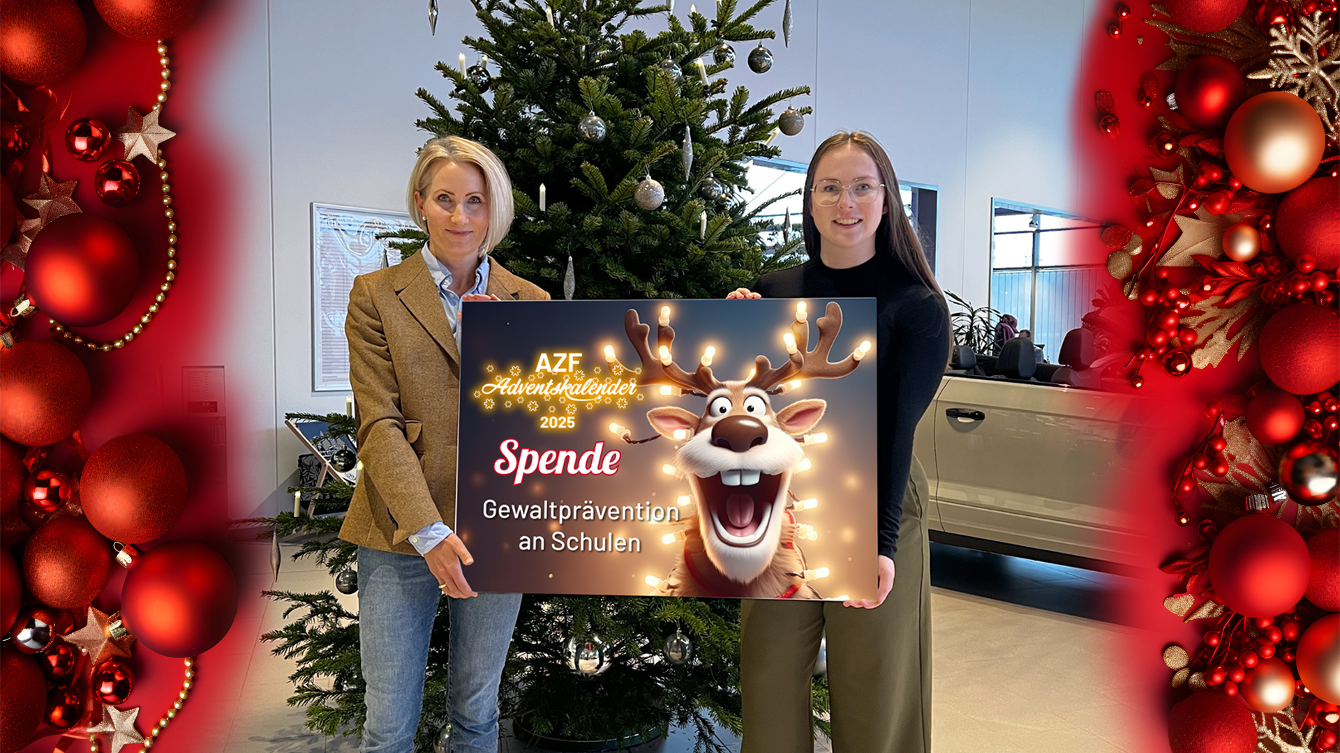 Zwei Personen halten eine Spendentafel auf der eine Spende für Gewaltprävention an Schulen steht, sie lächeln freundlich und stehen in einem Autohaus vor einem Weihnachtsbaum.